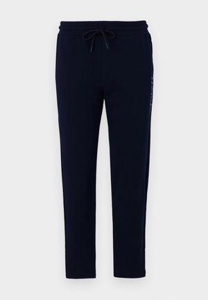 Pantalon bleu marine en tissu doux, doté d'une taille élastique avec lien de serrage et d'une coupe slim. Détail imprimé subtil sur le côté.