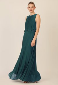 Teal geplooide maxi-jurk met een mouwloos ontwerp, gelaagd lijfje en zwierige rok. Zachte textuur, vloerlengte en subtiele draping aan de zoom.