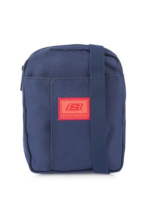 Bolso cruzado de tela azul marino con un parche de logo rojo y correa ajustable. Forma rectangular, cierre de cremallera y material texturizado duradero.