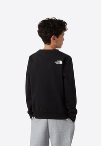 Must viiestitud dressipluus ümara kaelusega, millel on ülaosas taga väike valge logo. Valmistatud siledast puuvillasegust, lõdvestunud istuvusega.