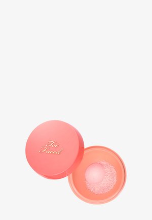 Runde, korallenfarbene Puderkompakt mit losem rosa Puder und goldenem "Too Faced"-Logo auf dem Deckel, offen auf weißem Hintergrund gezeigt.