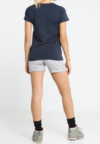 Marinblå t-shirt med kort ärm i kombination med ljusgrå shorts. Grå vandringsskor med röda accenter och svarta strumpor. En enkel, avslappnad outfit.