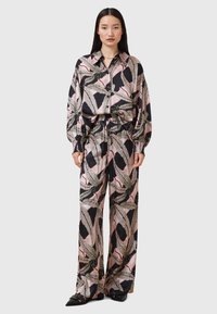 Completo due pezzi con motivo nero e rosa, composto da una camicia a maniche lunghe con bottoni e pantaloni a gamba larga, realizzato in tessuto morbido e leggero.