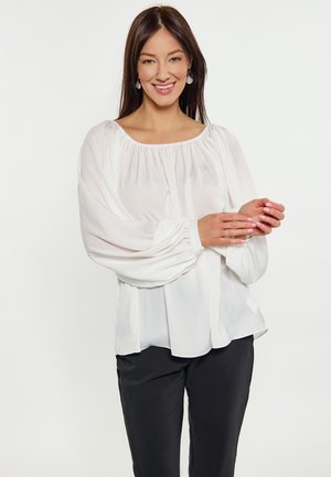 Weiße, leichte Bluse mit elastischem Halsausschnitt und weit ausgestellten Ärmeln, mit einer weichen, glatten Textur. Kombiniert mit schwarzen Hosen.