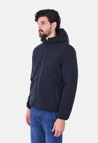 Giacca cappuccio blu navy con zip frontale, polsini elasticizzati e due tasche laterali. Realizzata in materiale morbido e leggero. Vestibilità casual.