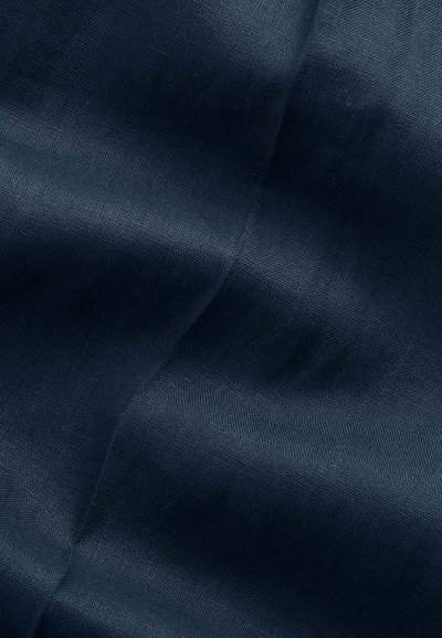 Tissu bleu foncé avec des plis subtils et une texture tissée lisse créant des ombres et des reflets doux.