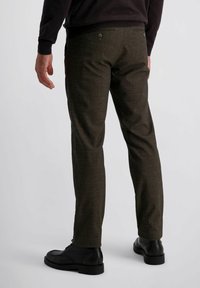 Bruine geruite broek in een textuurstof, met twee achterzakken met knopen en gecombineerd met zwarte enkellaarsjes.