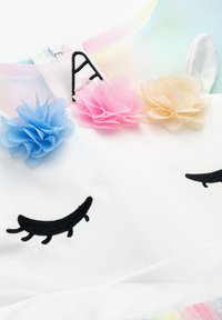 Unicorn-themed dress featuring a white fabric, mesh pastel upper, embroidered eyes, and fabric flowers in pink, blue, and cream.
