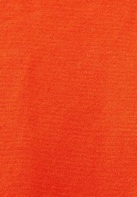 Tissu tricoté orange vif avec des coutures visibles dans un motif régulier et serré, montrant les détails de la texture et du tissage.