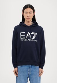 Hoodie blu navy realizzato in tessuto morbido, con tasca a marsupio, cappuccio con cordino e logo bianco EA7 Emporio Armani sulla parte anteriore.