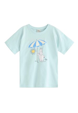 Lyseblå T-shirt med illustration af en hvid tegneseriefigur, der står under en blå- og hvidstribet strandparasol ved siden af en gul sol.