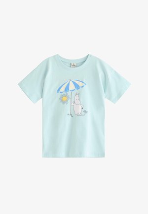 Lyseblå T-shirt med illustration af en hvid tegneseriefigur, der står under en blå- og hvidstribet strandparasol ved siden af en gul sol.