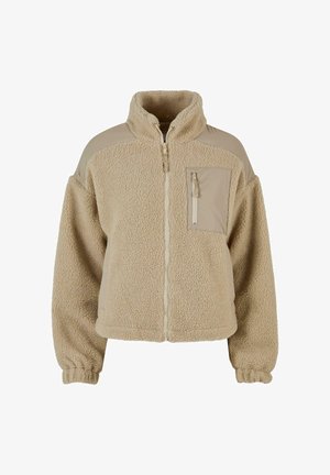 Beige fleecejack met een volledige rits aan de voorkant, hoge kraag, borstzak met rits en elastische boordjes aan de lange mouwen.