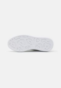 Suela de zapato con una superficie de goma blanca texturizada, que presenta un patrón único con surcos y contornos para ofrecer tracción.