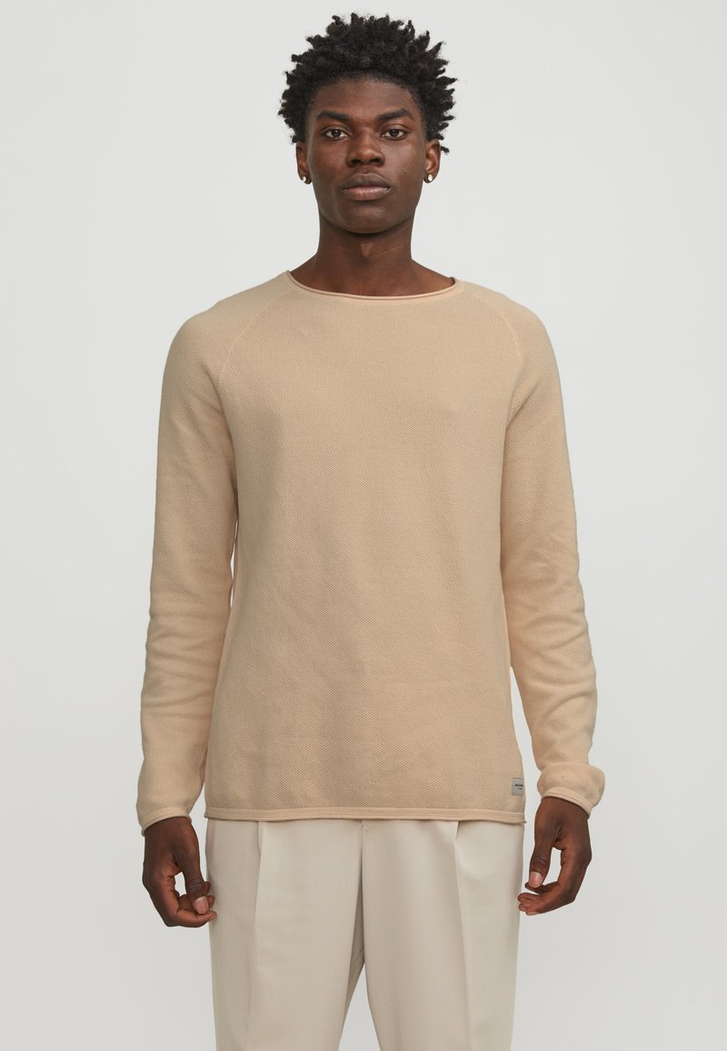 Beige gebreide trui met lange mouwen, ronde hals en een textuurstof. Heeft raglanmouwen en een label aan de onderzoom.