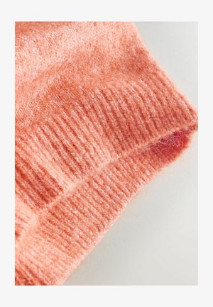 Manșetă de pulover de culoare piersică cu textura nervurată și suprafață moale, pufoasă, prezentând un design casual și cusături uniforme.