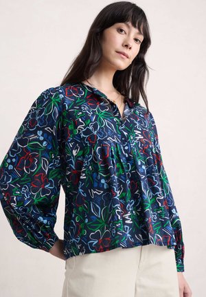 Bluse mit floralem Muster in Marineblau und langen Ärmeln, ausgestattet mit lebhaften roten, grünen und blauen Blumen, einem Button-Down-Kragen und Raffungselementen.