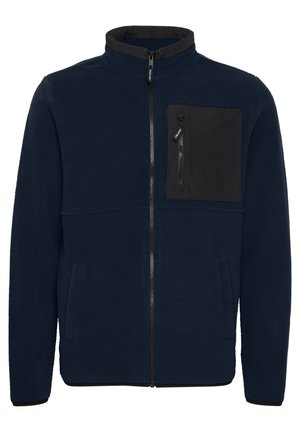 Chaqueta de forro polar de color navy con cuello alto, cremallera frontal y un bolsillo en el pecho de color negro. Cuenta con dos bolsillos laterales y un corte recto.