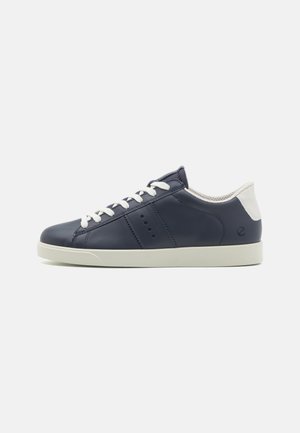 Zapatillas de cuero azul marino con acentos y cordones blancos. Presentan perforaciones y una suela de goma, con un diseño de punta redondeada.