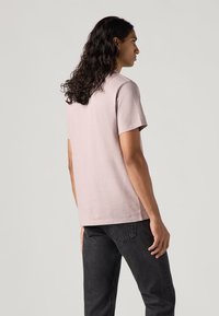 Lichtroze t-shirt met korte mouwen van zachte stof, met een klassieke ronde hals en een rechte snit, gecombineerd met donkere jeans.