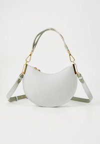 Sac à main rond en cuir gris clair avec une bandoulière réglable vert menthe et des éléments en métal doré. Texture lisse, design minimaliste.