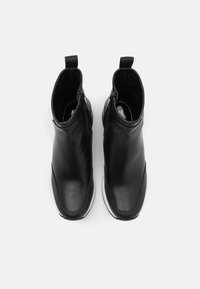 Stivaletti in pelle nera con un design elegante, superficie liscia e suole in gomma bianca. Presentano pannelli elastici ai lati e una linguetta sul retro per una facile calzata.