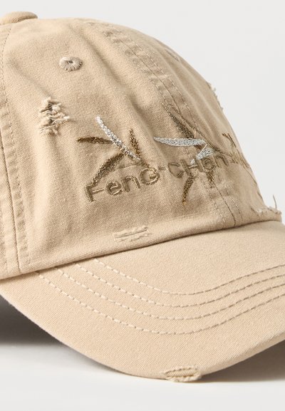 Μπεζ φθαρμένο καπέλο μπέιζμπολ με κεντημένα φύλλα και μερικώς ορατό κείμενο "Fene'Ce" στο μπροστινό πάνελ.