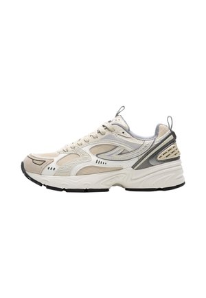 Beige en witte sportschoen met meshpanelen, dikke gevoerde zool, veters aan de voorkant en grijze accenten op hiel en zijkanten.