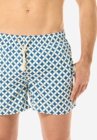 Blaue Badehose aus leichtem Stoff mit einem geometrischen Muster in Creme. Mit einem Zugbandverschluss und einem dekorativen Knoten-Detail.