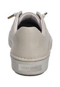 Zapatilla de cuero beige claro con forma redondeada, talón texturizado, cordones elásticos y suela de goma marrón, que exhibe un logo en la parte trasera.
