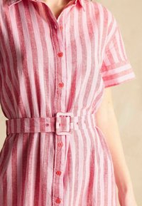 Rosa und weiße gestreifte Leinenkleid mit einem kragenförmigen Ausschnitt, kurzen Ärmeln und einem passenden Gürtel. Mit Knopfleiste vorne und strukturiertem Stoff.