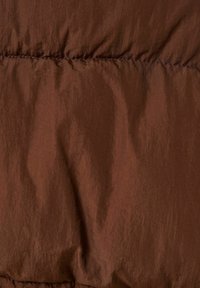 Tessuto in giacca puffer marrone con una texture liscia e leggermente increspata e linee di cucitura visibili, che mette in risalto una ricca tonalità di cioccolato scuro.