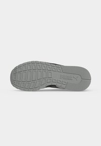 Semelle en caoutchouc grise d'une chaussure Puma avec un motif de bande de roulement texturé et le logo de la marque visible sur la zone du talon.
