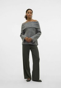 Szürke vállakat szabadon hagyó pulóver bordázott mintával, bőszárú olíva zöld nadrággal és mintás bebújós cipővel párosítva.