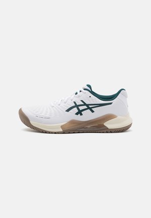 Zapatilla deportiva blanca con acentos verdes, parte superior texturizada y amortiguación soporte. Presenta una suela de goma para tracción y durabilidad.