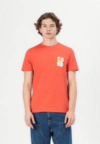 Orange bomulds-T-shirt med rund halsudskæring og korte ærmer, med hvidt grafisk tekst og smiley ansigt på venstre bryst.
