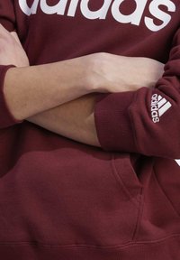 adidas Sportswear ESSENTIALS LINEAR - Mikina s kapucňou - shadow red   white