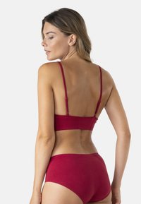 Ensemble soutien-gorge rouge et culotte taille haute assortie. Tissu lisse avec bretelles ajustables sur le soutien-gorge. Design simple, sans motifs visibles.