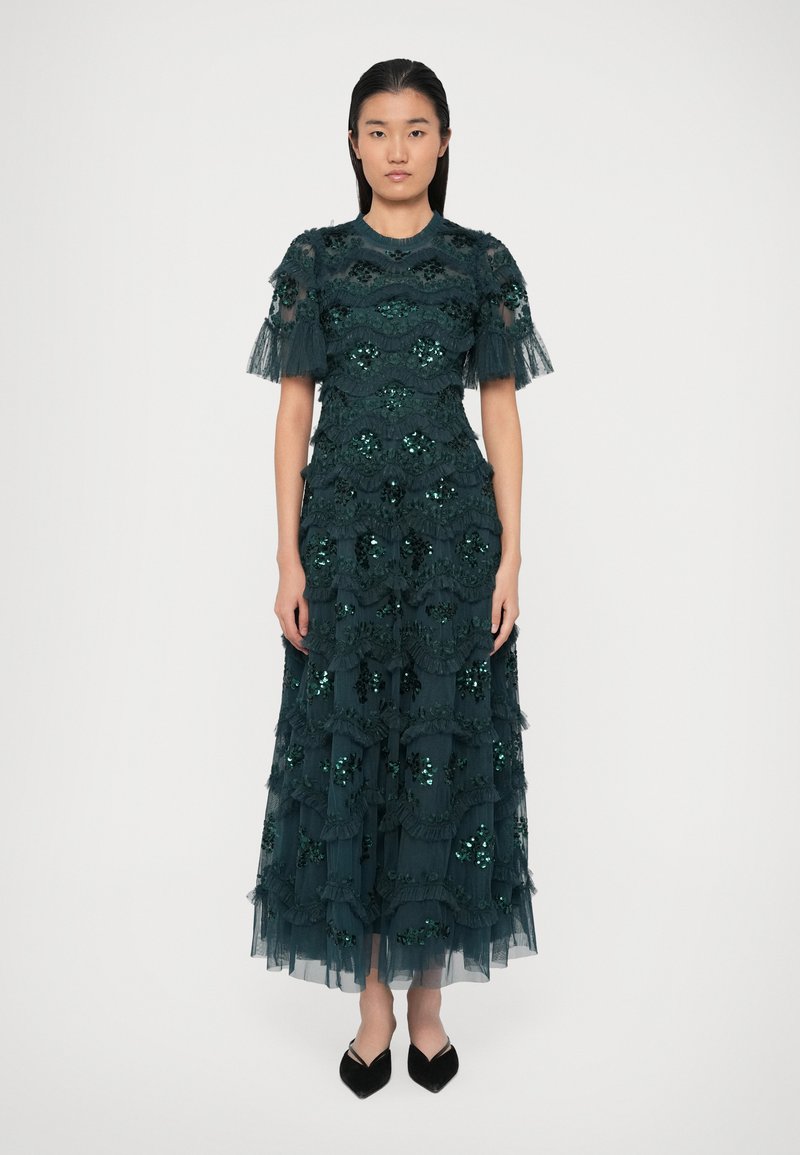 Dunkelblaugrünes Kleid mit geschichteten Rüschen, verziert mit Pailletten und fransigen Ärmeln. Aus durchsichtigem Tüll gefertigt, mit einer fließenden Silhouette.