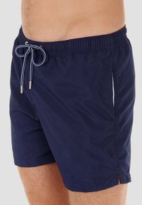 Marinefarbene Schwimmshorts mit elastischem Taillenbund, verstellbarem Kordelzug und Seitentaschen mit weißen Akzenten. Leichtes Material.