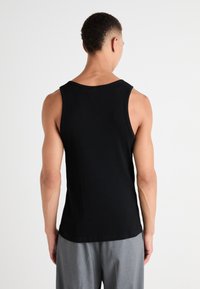 Débardeur noir sans manches en tissu doux, avec un col arrondi et une coupe nette à l'ourlet, vu de dos.