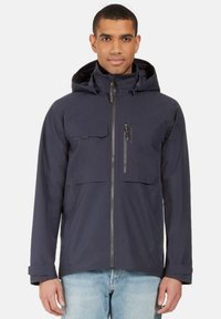 Laivastonsininen takki, jossa on etuvetoketju, kaksi suurta rintataskua ja säädettävä huppu. sileä kangas ja tyylikäs, nykyaikainen muotoilu.