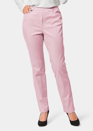 Pantalons rose clair avec une texture lisse, dotés d'une taille élastique, de poches latérales et d'un design à jambes droites, assortis à des talons noirs.