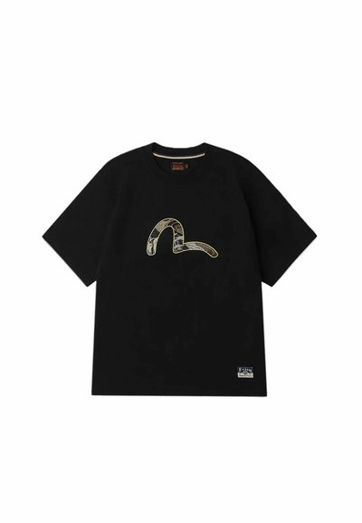 T-shirt en coton noir à manches courtes, avec un graphisme texturé en forme de serpent doré sur le devant et une petite étiquette en bas à gauche.