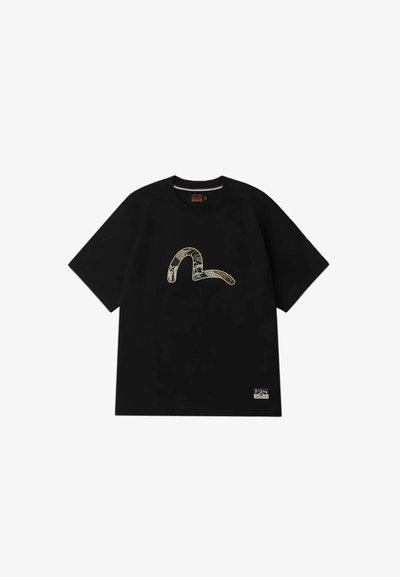 T-shirt en coton noir à manches courtes, avec un graphisme texturé en forme de serpent doré sur le devant et une petite étiquette en bas à gauche.