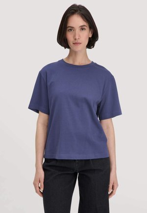 Lila Baumwoll-T-Shirt mit kurzen Ärmeln, Rundhalsausschnitt und lockerer Passform. Glatte Textur und dezente Nahtdetails am Saum.