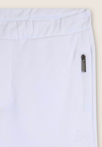 Pantalones deportivos blancos con cinturilla elástica, que cuentan con un pequeño bolsillo con cremallera y un bordado de la marca en la parte baja de la pierna. Textura suave.
