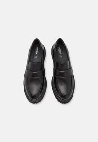 Mocassins en cuir noir avec une finition lisse et une large sangle sur le cou-de-pied. Semelle en caoutchouc texturé avec un motif de semelle pour une meilleure adhérence. Marque Geox à l'intérieur.