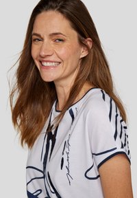 White T-shirt featuring a navy blue abstract design and accents. Short sleeves with contrasting blue trim. Soft cotton material.