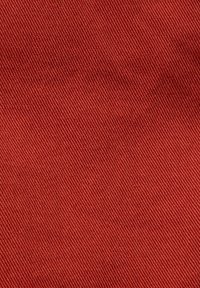 Gros plan d’un tissu rouge avec une texture côtelée diagonale montrant les détails fins du matériau tissé.
